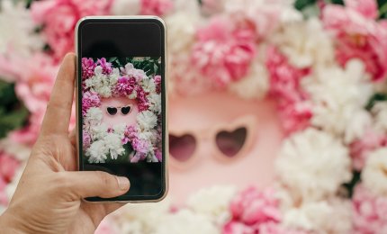 a phone camera taking a photo of flowers and sunglasses